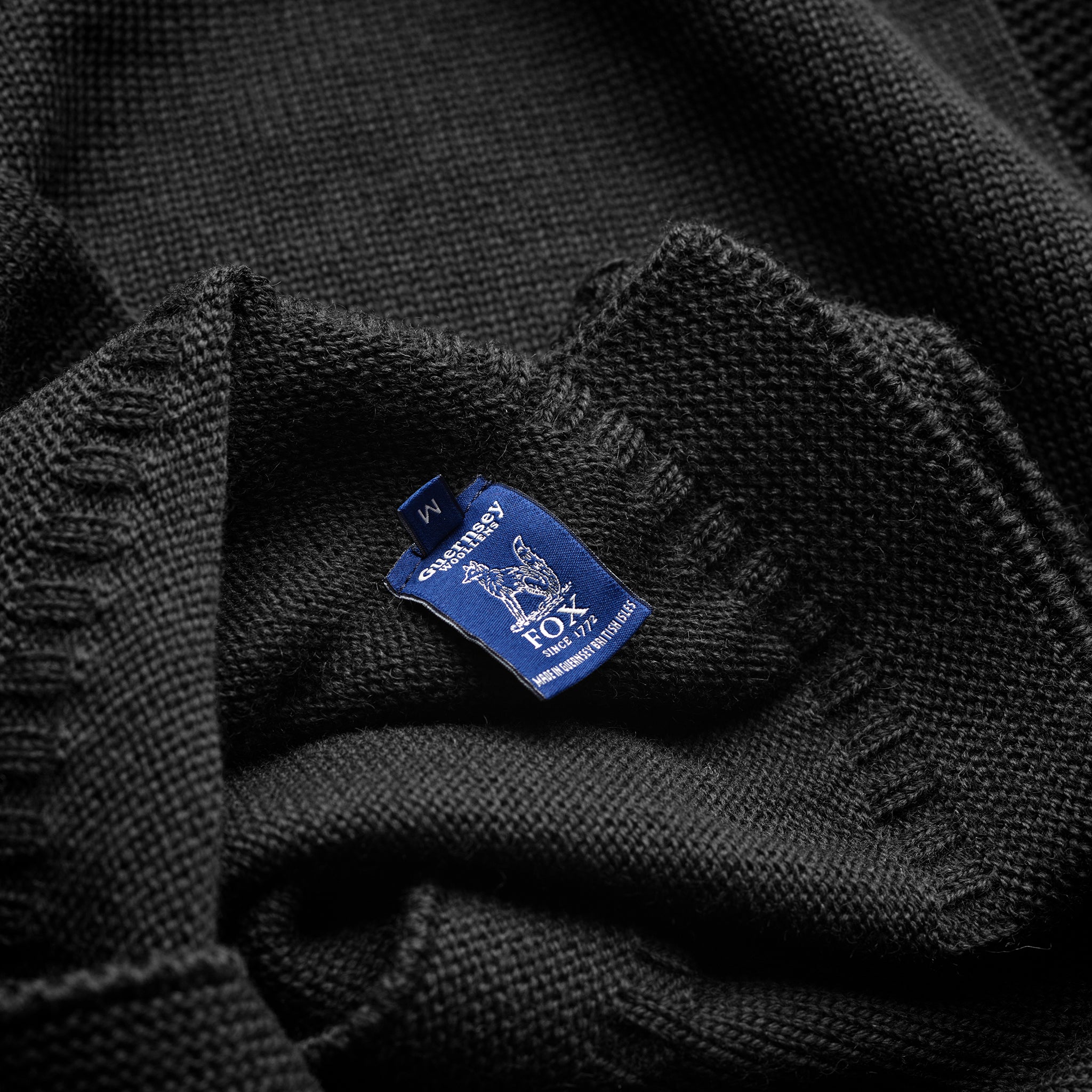 Inside label detail of the Guernsey Woollens x Fox roll neck knit in Midnight Black